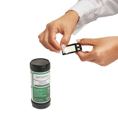 A person peels a white label from a black plastic cartridge beside a green and black cylinder labeled Heavy-Duty Stand Alone LB (Leave Behind), an odor control product.