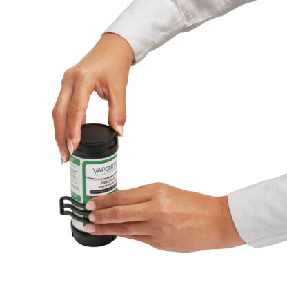 Two hands open a black plastic container labeled Heavy-Duty Stand Alone LB (Leave Behind) with a latch mechanism. The person opening it is wearing a white long-sleeve shirt.